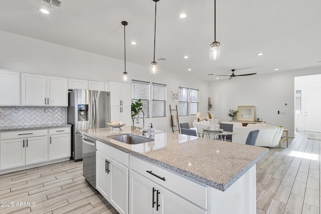 15718 W Polk St, Goodyear, AZ 85338 - kitchen with a sink, appliances with stainless steel finishes, tasteful backsplash, ceiling fan, and a center island with sink