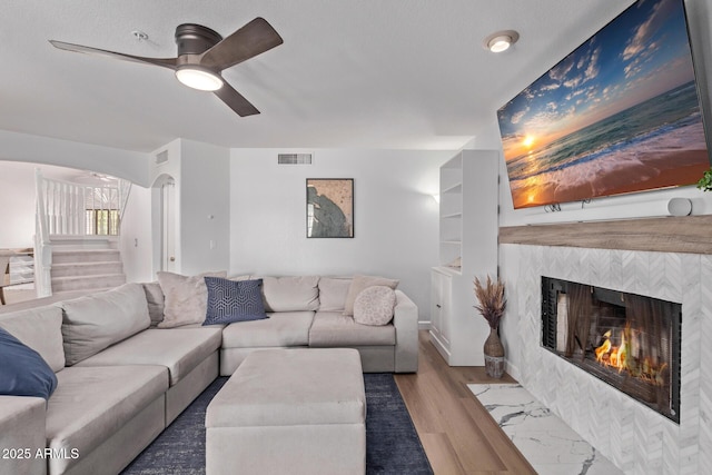 living area with ceiling fan, stairs, wood finished floors, and visible vents