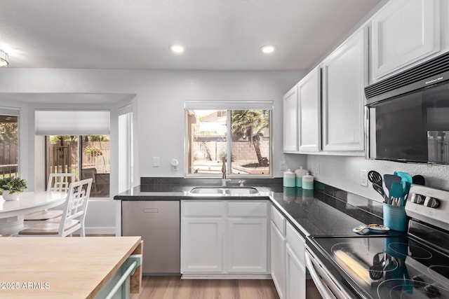 kitchen with white cabinets, black microwave, a sink, light wood finished floors, and electric stove