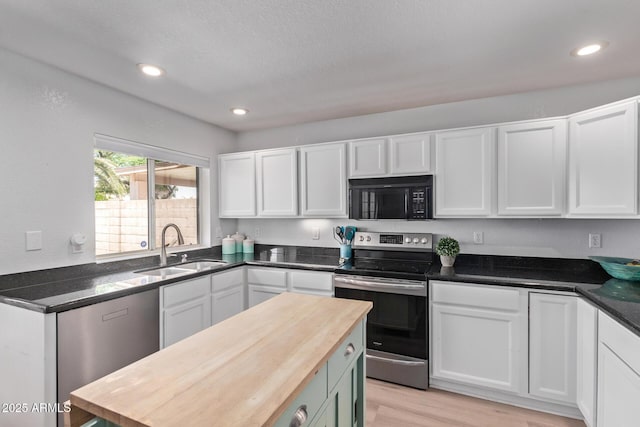 kitchen with black microwave, a sink, light wood finished floors, electric stove, and white cabinetry