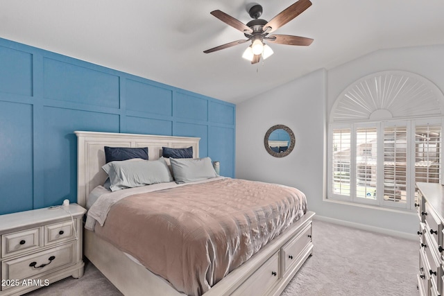 bedroom featuring a ceiling fan, light carpet, lofted ceiling, and a decorative wall