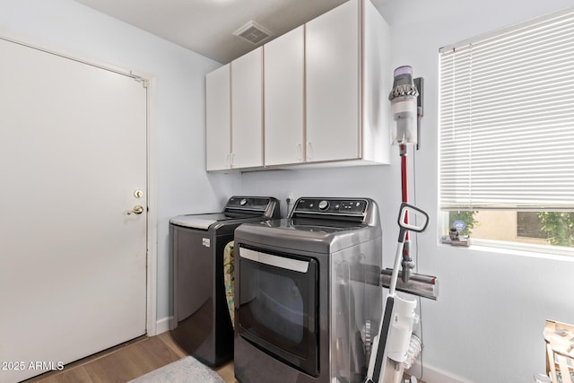 laundry room featuring visible vents, baseboards, cabinet space, washing machine and clothes dryer, and light wood-style flooring