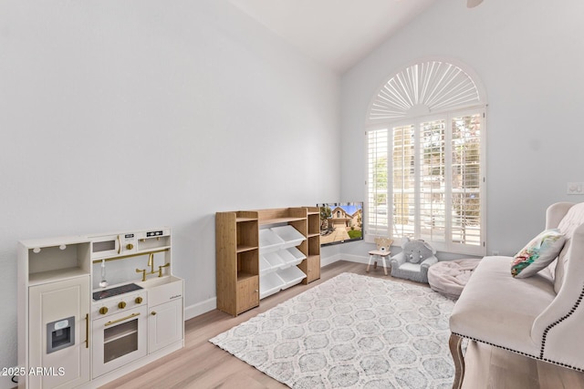 sitting room featuring baseboards, light wood-type flooring, and lofted ceiling