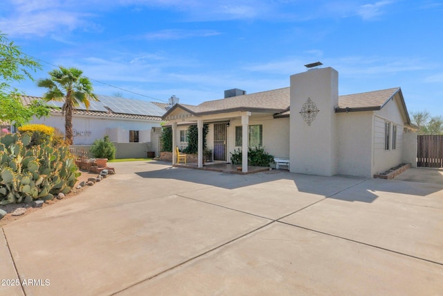 view of front of house featuring stucco siding, a chimney, and fence