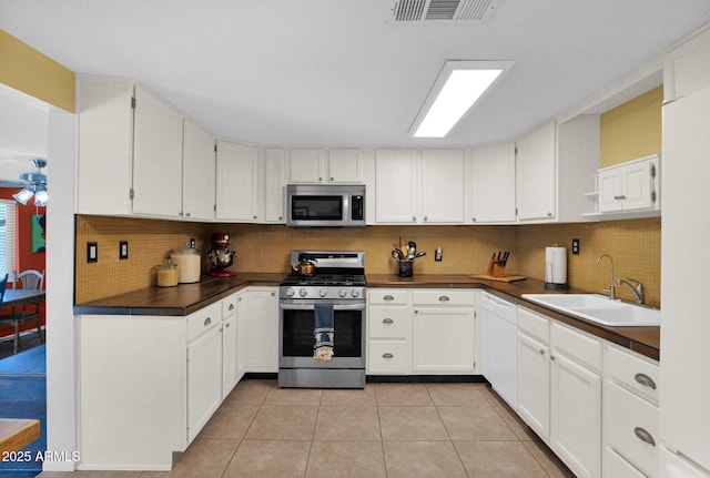 kitchen featuring visible vents, a sink, dark countertops, appliances with stainless steel finishes, and light tile patterned floors