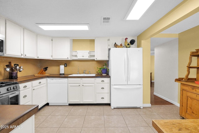 kitchen featuring dark countertops, visible vents, a sink, white appliances, and open shelves