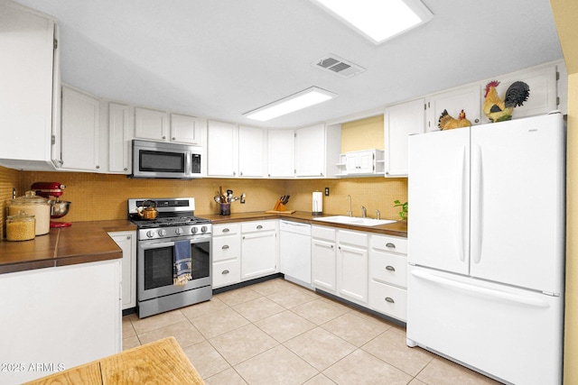 kitchen featuring visible vents, a sink, light tile patterned floors, appliances with stainless steel finishes, and open shelves