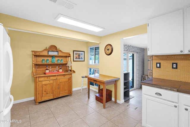 home office with light tile patterned floors, visible vents, and baseboards