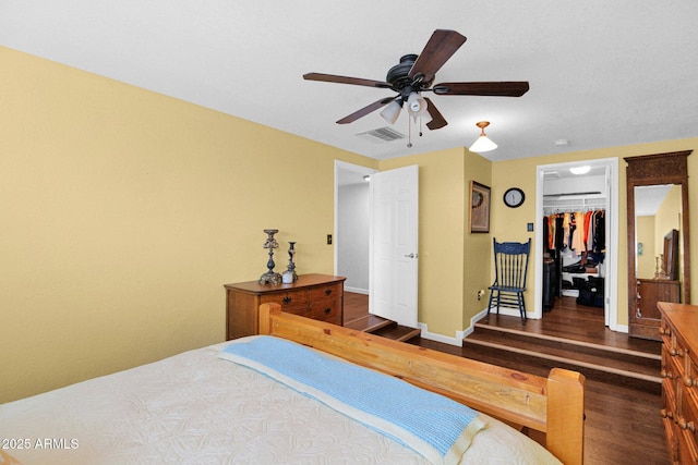 bedroom with visible vents, a ceiling fan, wood finished floors, a closet, and baseboards