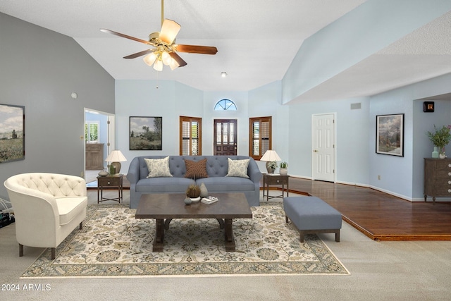 living room featuring high vaulted ceiling, wood finished floors, carpet flooring, baseboards, and ceiling fan