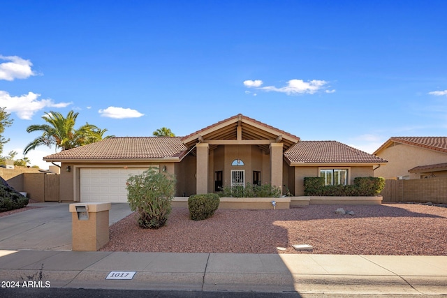 view of front of home with a tile roof, fence, driveway, and stucco siding