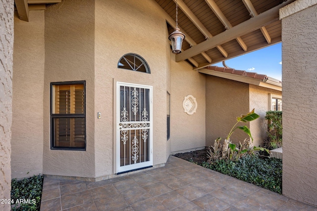 entrance to property with a tile roof and stucco siding