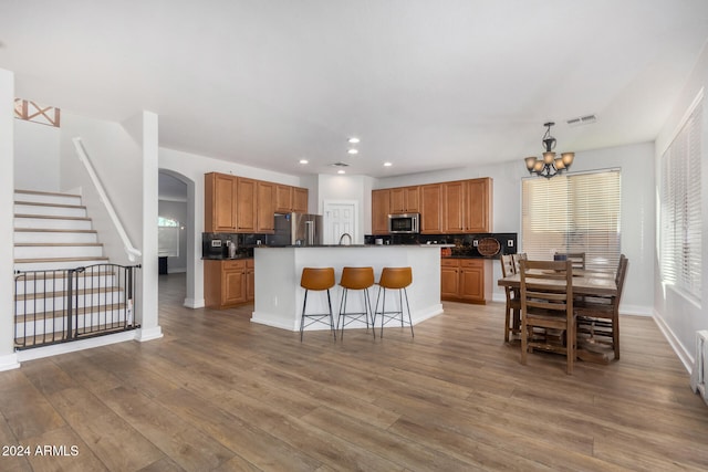 kitchen featuring appliances with stainless steel finishes, hardwood / wood-style flooring, a center island, and backsplash