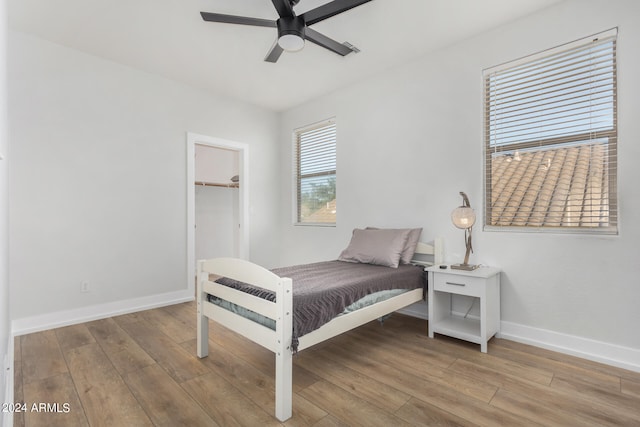 bedroom with a spacious closet, light hardwood / wood-style floors, and ceiling fan