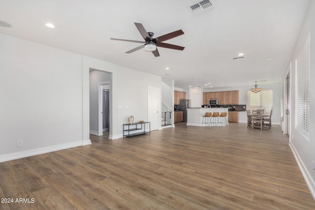 unfurnished living room featuring dark hardwood / wood-style flooring and ceiling fan with notable chandelier