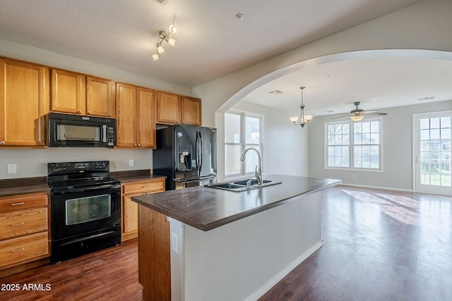 kitchen featuring black appliances, ceiling fan with notable chandelier, sink, hanging light fixtures, and an island with sink