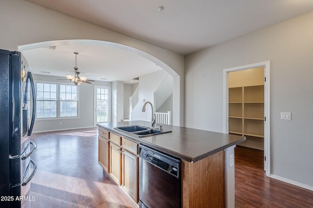 kitchen with ceiling fan, sink, black appliances, dark hardwood / wood-style floors, and an island with sink