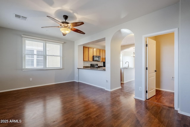 unfurnished living room with ceiling fan, sink, and dark hardwood / wood-style floors