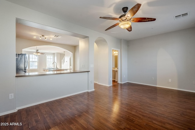 unfurnished living room featuring dark hardwood / wood-style floors, ceiling fan, and sink