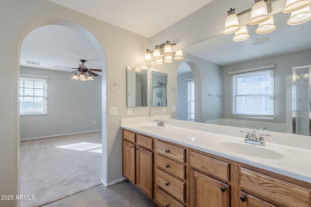 bathroom featuring tile patterned flooring, vanity, ceiling fan with notable chandelier, and walk in shower