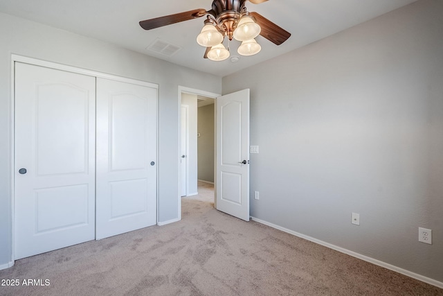 unfurnished bedroom featuring ceiling fan, a closet, and light carpet