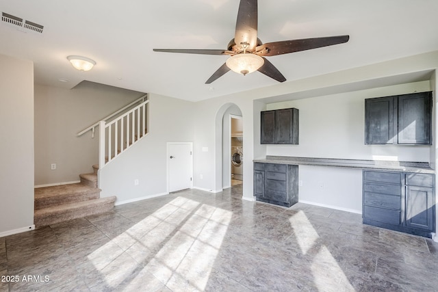 unfurnished living room featuring ceiling fan and washer / dryer