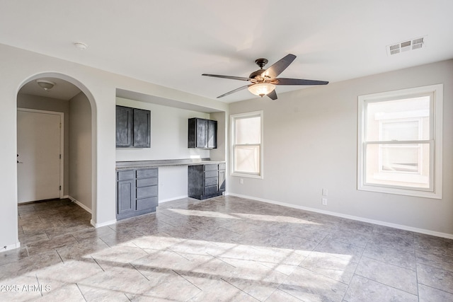 unfurnished living room featuring ceiling fan and built in desk