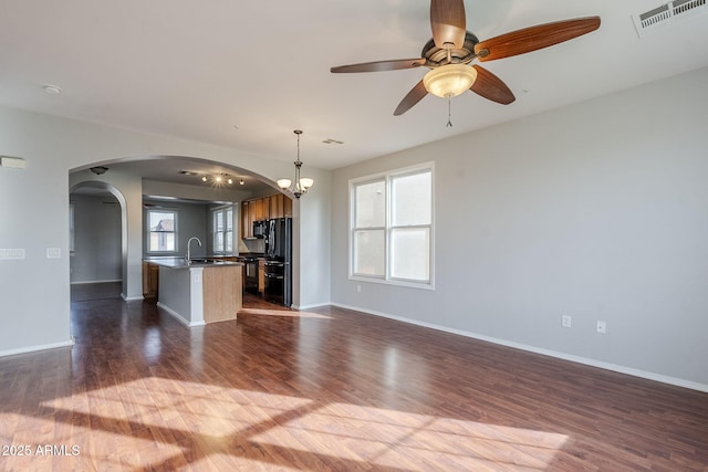 unfurnished living room featuring sink, dark wood-type flooring, and ceiling fan with notable chandelier