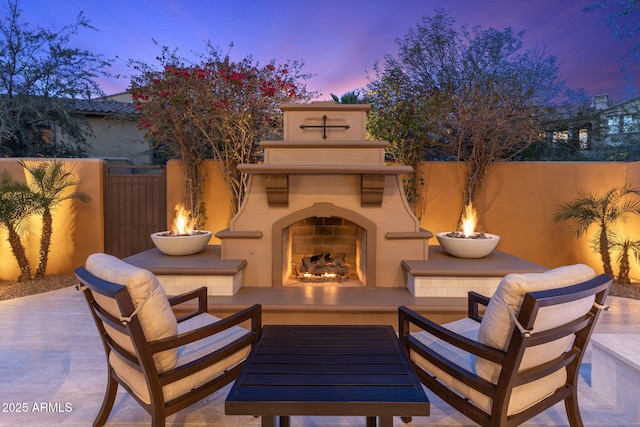 patio terrace at dusk with an outdoor fireplace