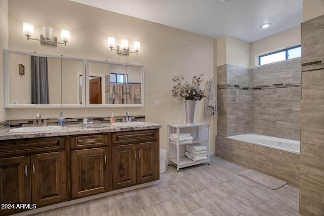 bathroom with vanity and tiled tub