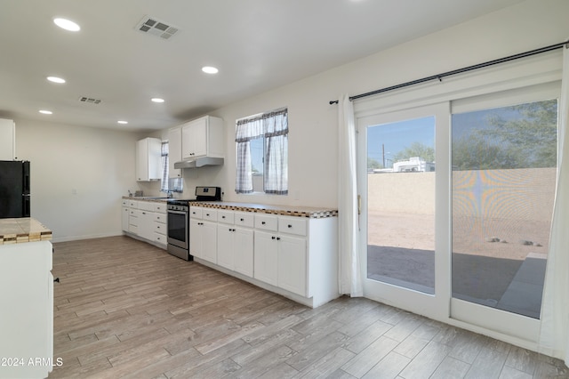 kitchen with black fridge, sink, stainless steel range oven, light hardwood / wood-style flooring, and white cabinets