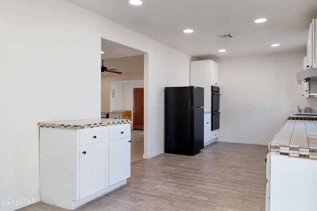 kitchen with black appliances, white cabinetry, exhaust hood, ceiling fan, and light hardwood / wood-style flooring