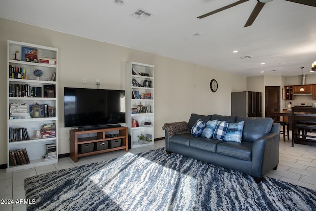 tiled living room featuring ceiling fan with notable chandelier and built in shelves