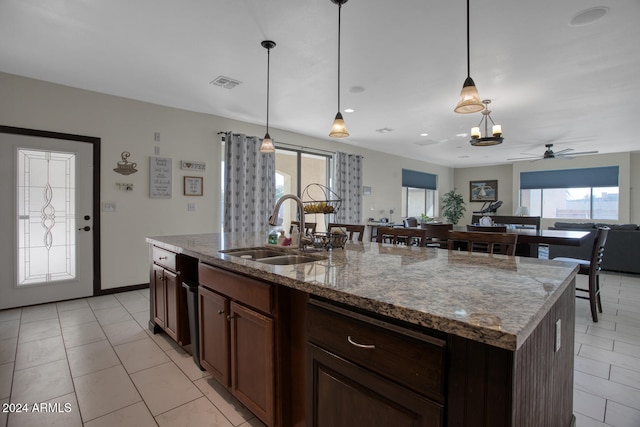 kitchen with light stone countertops, a wealth of natural light, sink, and a kitchen island with sink