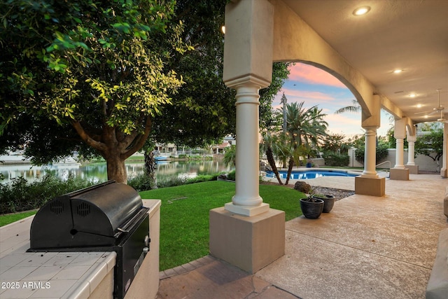 1507 E Treasure Cove Dr, Gilbert, AZ 85234 - patio terrace at dusk featuring a lawn, a water view, an outdoor pool, and grilling area
