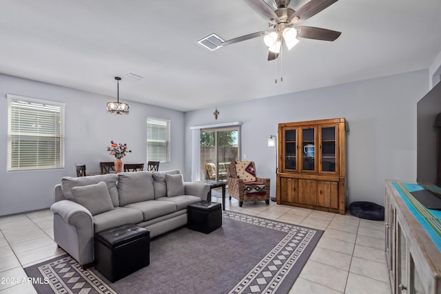 tiled living room with ceiling fan with notable chandelier