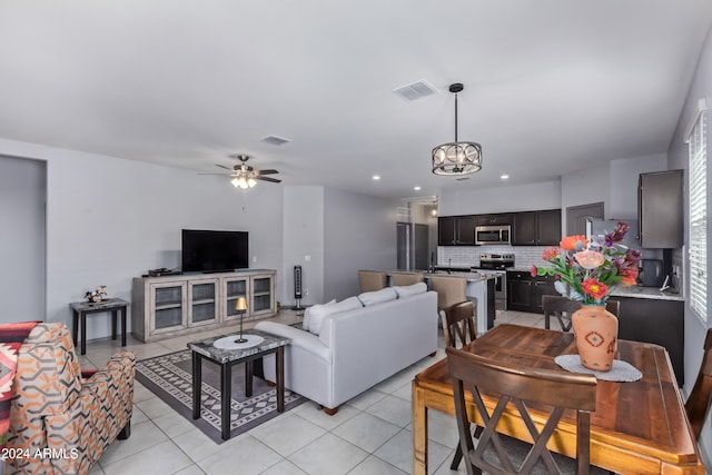 tiled living room with ceiling fan with notable chandelier