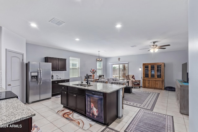 kitchen with dark brown cabinetry, sink, an island with sink, stainless steel refrigerator with ice dispenser, and light tile patterned floors