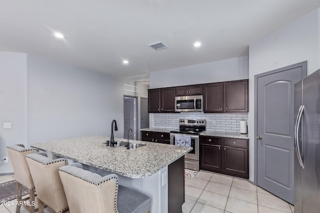 kitchen featuring stainless steel appliances, a breakfast bar, sink, a center island with sink, and light tile patterned floors