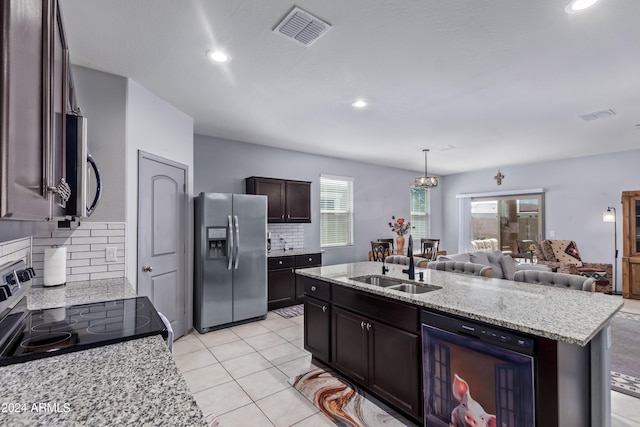 kitchen with dark brown cabinetry, stainless steel appliances, beverage cooler, sink, and a center island with sink