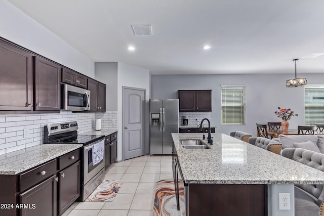 kitchen featuring dark brown cabinetry, stainless steel appliances, sink, a breakfast bar area, and light tile patterned floors