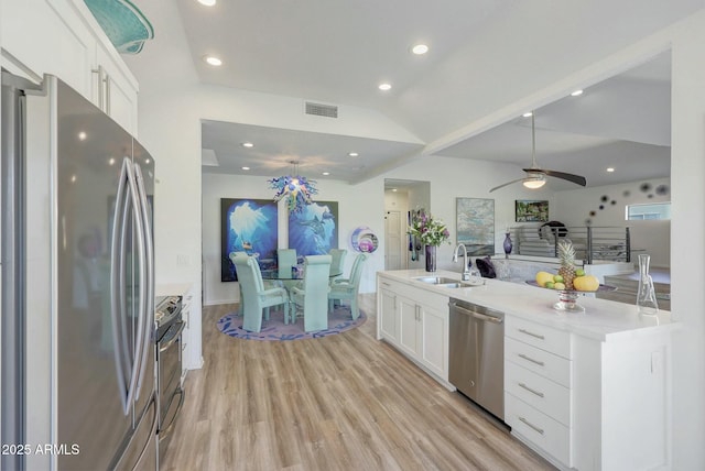 kitchen with sink, stainless steel appliances, light hardwood / wood-style floors, white cabinets, and vaulted ceiling