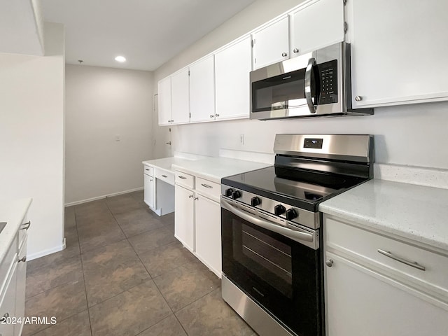 kitchen featuring stainless steel appliances, white cabinetry, and dark tile patterned flooring