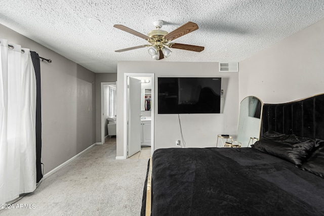 bedroom with light colored carpet, connected bathroom, ceiling fan, and a textured ceiling