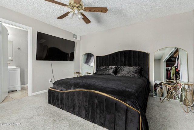 bedroom with a textured ceiling, ceiling fan, light carpet, and ensuite bathroom