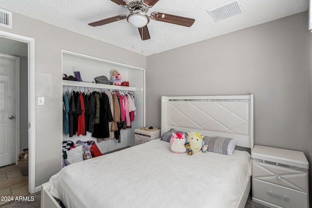 bedroom with a textured ceiling, hardwood / wood-style flooring, ceiling fan, and a closet