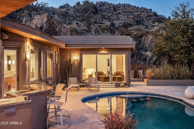 view of pool with an outdoor wet bar and a patio area