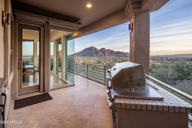 patio terrace at dusk featuring a balcony and a mountain view