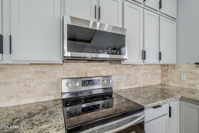 kitchen featuring white cabinetry, appliances with stainless steel finishes, light stone countertops, and decorative backsplash