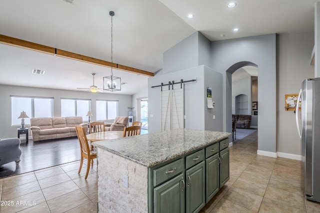 kitchen featuring pendant lighting, stainless steel refrigerator, a center island, a barn door, and beam ceiling